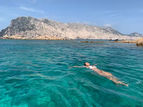 Mujer flotando de espaldas en agua turquesa, calma y presencia en la naturaleza