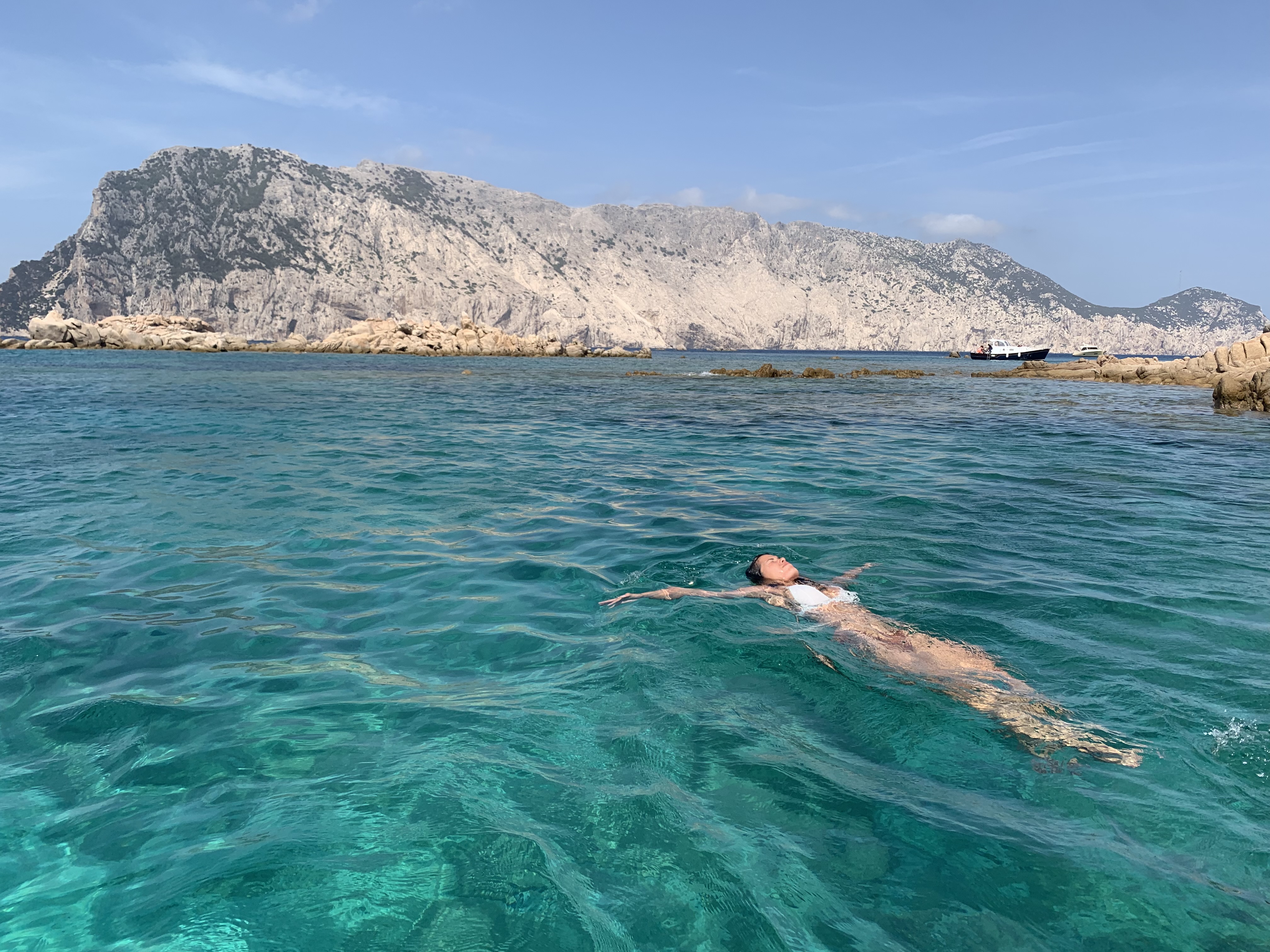 Mujer flotando de espaldas en agua turquesa, calma y presencia en la naturaleza